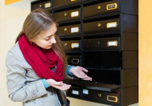 A woman looks into an empty mailbox with disappointment and wonders how to track a settlement check. 