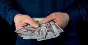 A man holds a pile of cash after finding out what a structured settlement loan is.