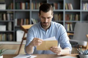 A man opening mail. Learn about whether your lawsuit check can come in the mail.