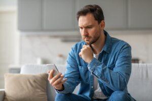 A man on his phone researching how much a wrongful arrest lawsuit is worth.