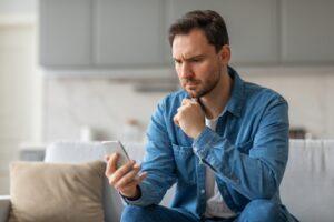 A man on his phone researching how much a wrongful arrest lawsuit is worth.