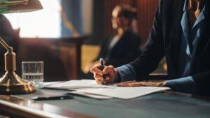 A lawyer writing on a document how much it costs to sue someone