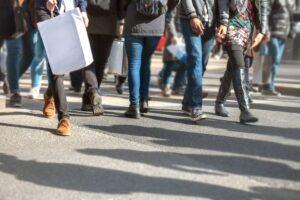 A large crowd of people crossing a road. You can learn more about how much a pedestrian accident settlement is worth today.