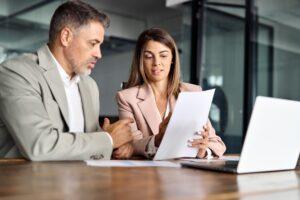 A lawyer sits at her desk with a client, sharing a piece of paper and explaining why Pegasus Legal Capital is right for him.