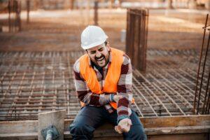 An injured construction worker grasps his arm and wonders how much a construction accident lawsuit is worth.